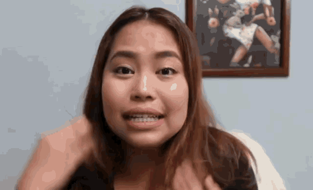 a woman with braces on her teeth is making a funny face in front of a picture of a woman .