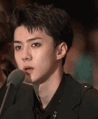 a young man is sitting in front of a microphone and talking into it .