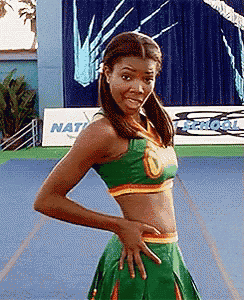 a cheerleader is posing for a picture with her hands on her hips while wearing a green top and skirt .