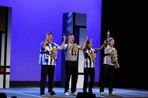 a group of men wearing blue and white striped shirts are holding stuffed animals in their arms