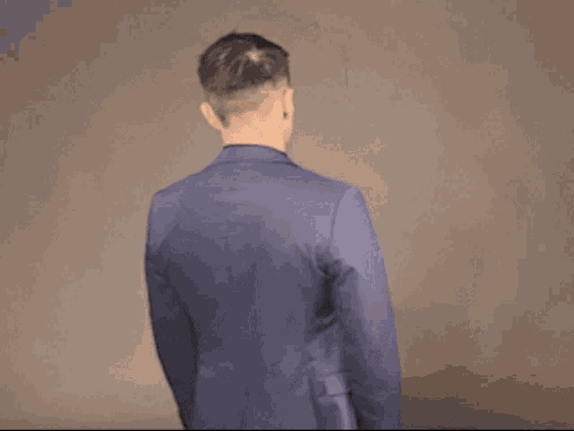 a man in a blue suit is making a gesture