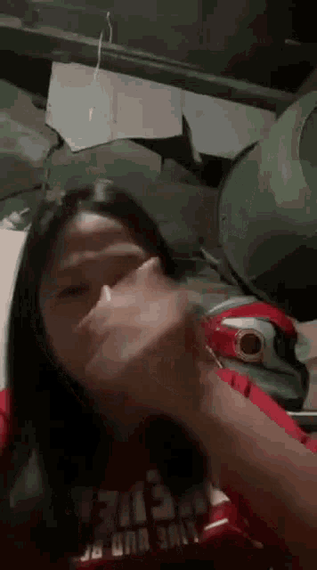 a girl wearing a red shirt with the word america on it is covering her mouth with her hand .