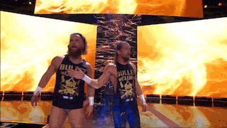 two men wearing bullet club tank tops are walking in front of flames