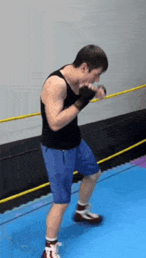 a man in a black tank top and blue shorts is boxing