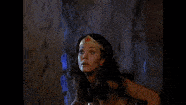 a woman in a wonder woman costume is being lifted by a man in a cave .