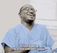 a man in a blue scrub top is laughing and saying i 'm just kidding .
