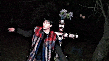 a man standing in front of a cross with flowers on it