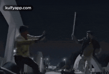 a man is fighting another man with a sword in a dark room with the website kulfyapp.com in the corner .