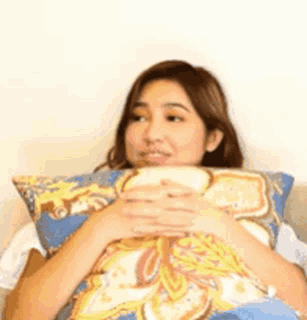 a woman is laying on a couch holding a pillow in her lap .