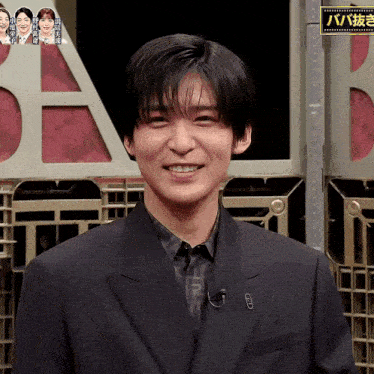 a man in a suit is smiling in front of a sign that says a