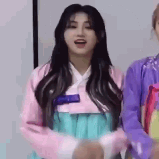 a woman in a pink kimono is standing next to another woman in a purple shirt .