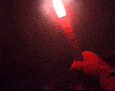 a red candle is lit in the dark with a flame coming out of it