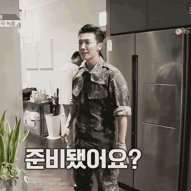 a man in a military uniform is standing in front of a refrigerator with korean writing on the door