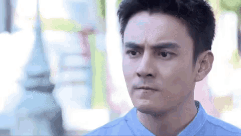 a man in a blue shirt is making a funny face and looking at the camera .