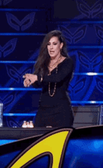 a woman in a black dress is standing in front of a blue and yellow background