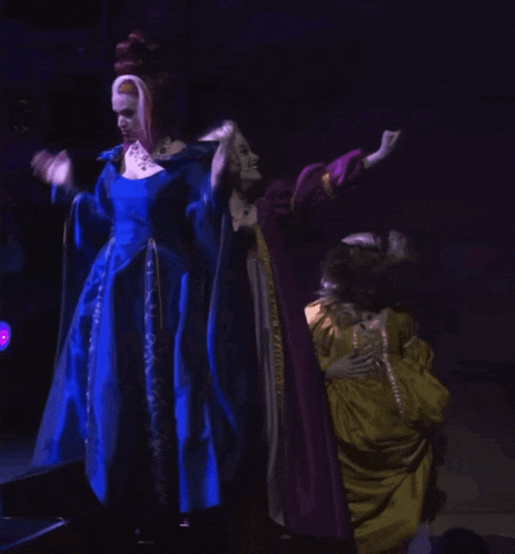 a woman in a blue dress is standing next to a woman in a purple dress