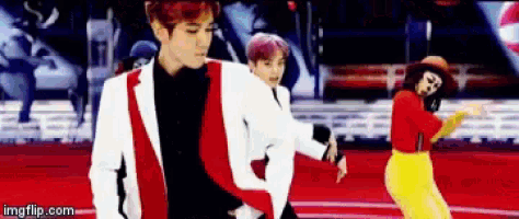 a man in a red and white suit is dancing with two other people .