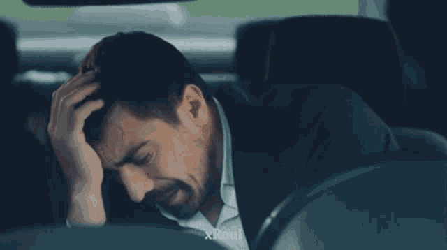 a man is sitting in the back seat of a car with xroui written on the bottom right
