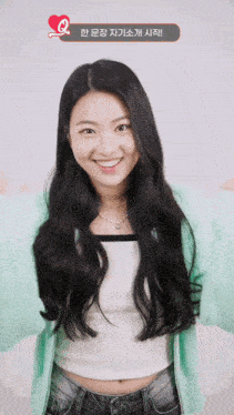 a woman with long black hair is smiling in front of a sign that says " q "
