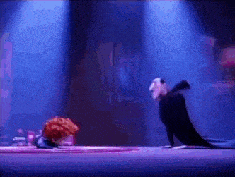 a couple of cartoon characters are standing next to each other on a stage in a dark room .