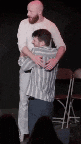 two men hugging each other on stage in front of a crowd