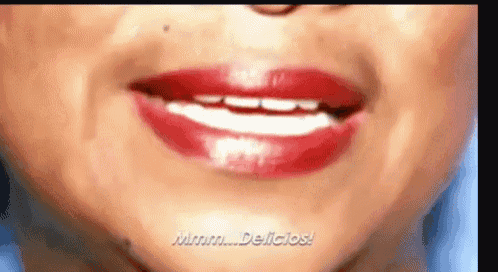 a close up of a woman 's mouth with red lipstick and the words mmmm delicious .