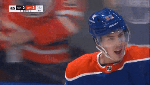 a hockey player wearing a blue helmet and an orange and white jersey