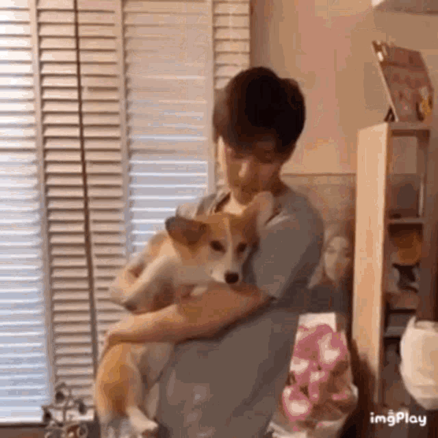 a man is holding a small dog in his arms in a living room .