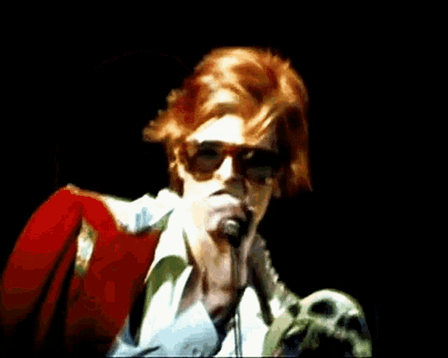 a man singing into a green microphone with red hair