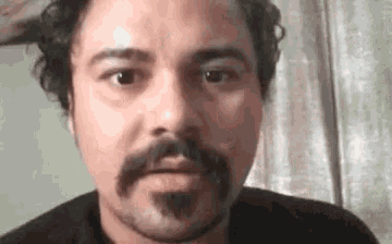 a close up of a man with a beard and mustache making a funny face .