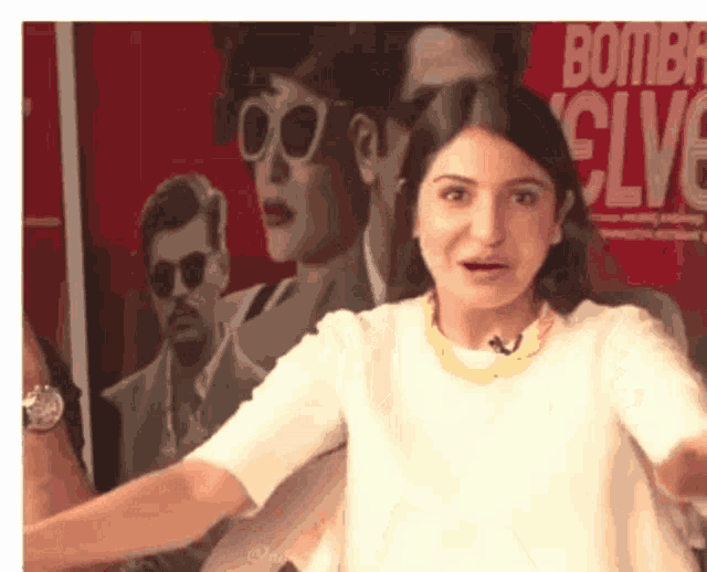 a woman wearing sunglasses stands in front of a poster that says bombay evolve