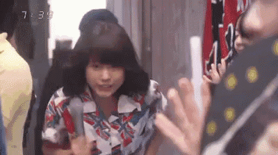 a woman in a colorful shirt is holding a knife in her hand while standing in a crowd of people .