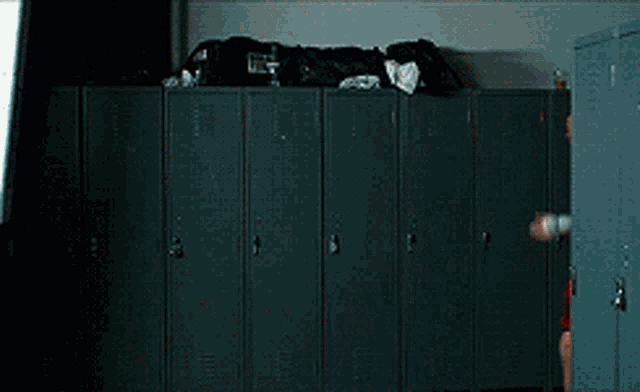a shirtless man in red shorts is standing in front of lockers