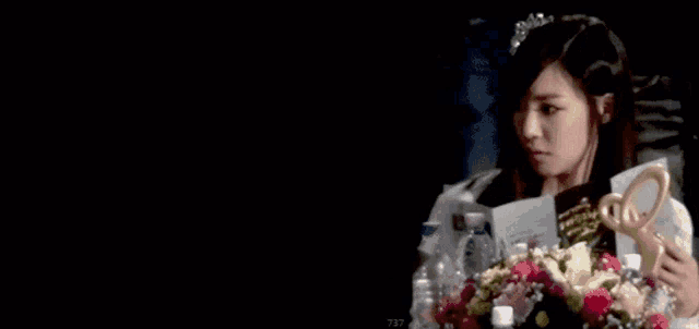 a woman holding a bouquet of flowers and a trophy with the number 737 on the bottom right