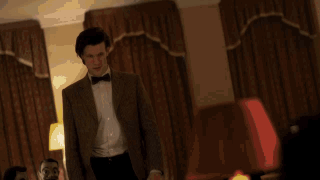 a man wearing a bow tie and a suit looks at the camera
