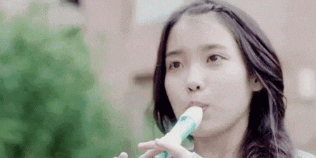 a young woman is playing a flute in her mouth .