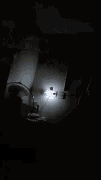 a fan is lit up in a dark room next to a light bulb