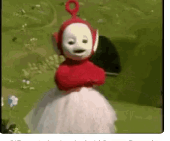 a teletubbies character is standing in a field with his arms crossed .