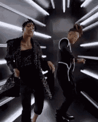 two women are dancing in a dark room with lights on the wall .