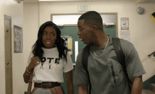 a man and a woman are standing next to each other in a hallway with an exit sign above them