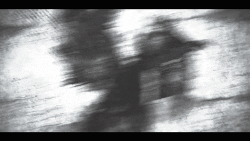 a blurry black and white photo of a person walking on a street .