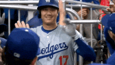 a baseball player for the dodgers is giving a high five to a teammate .