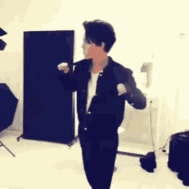 a man in a black jacket stands in a room