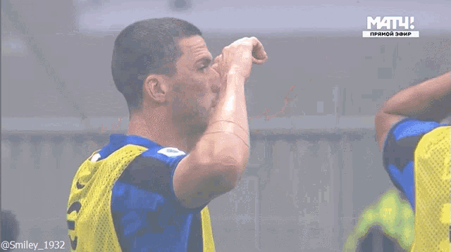 a man in a blue and yellow jersey with the number 1932 on the back