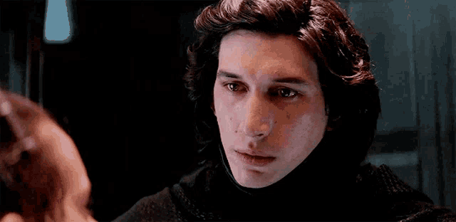a close up of a man 's face with a woman behind him in a dark room .