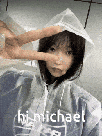 a girl wearing a raincoat says hi michael