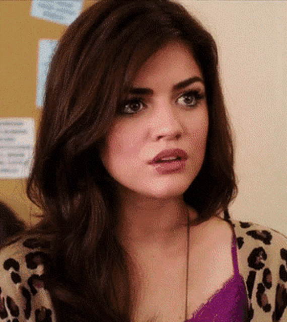 a close up of a woman 's face wearing a purple top and a leopard print sweater