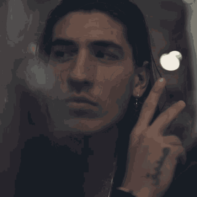 a close up of a man 's face with a tattoo on his wrist that says ' a '
