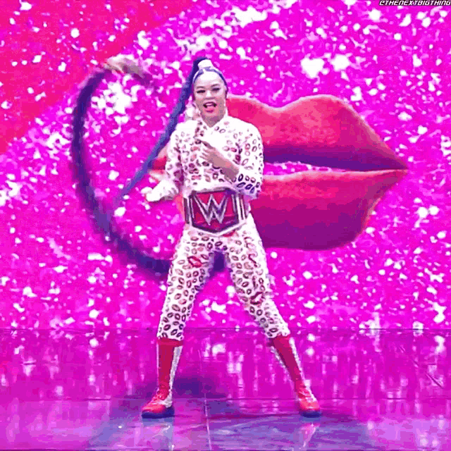 a woman in a leopard print outfit is standing in front of a pink background .