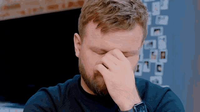 a man covering his face with his hand while wearing an apple watch